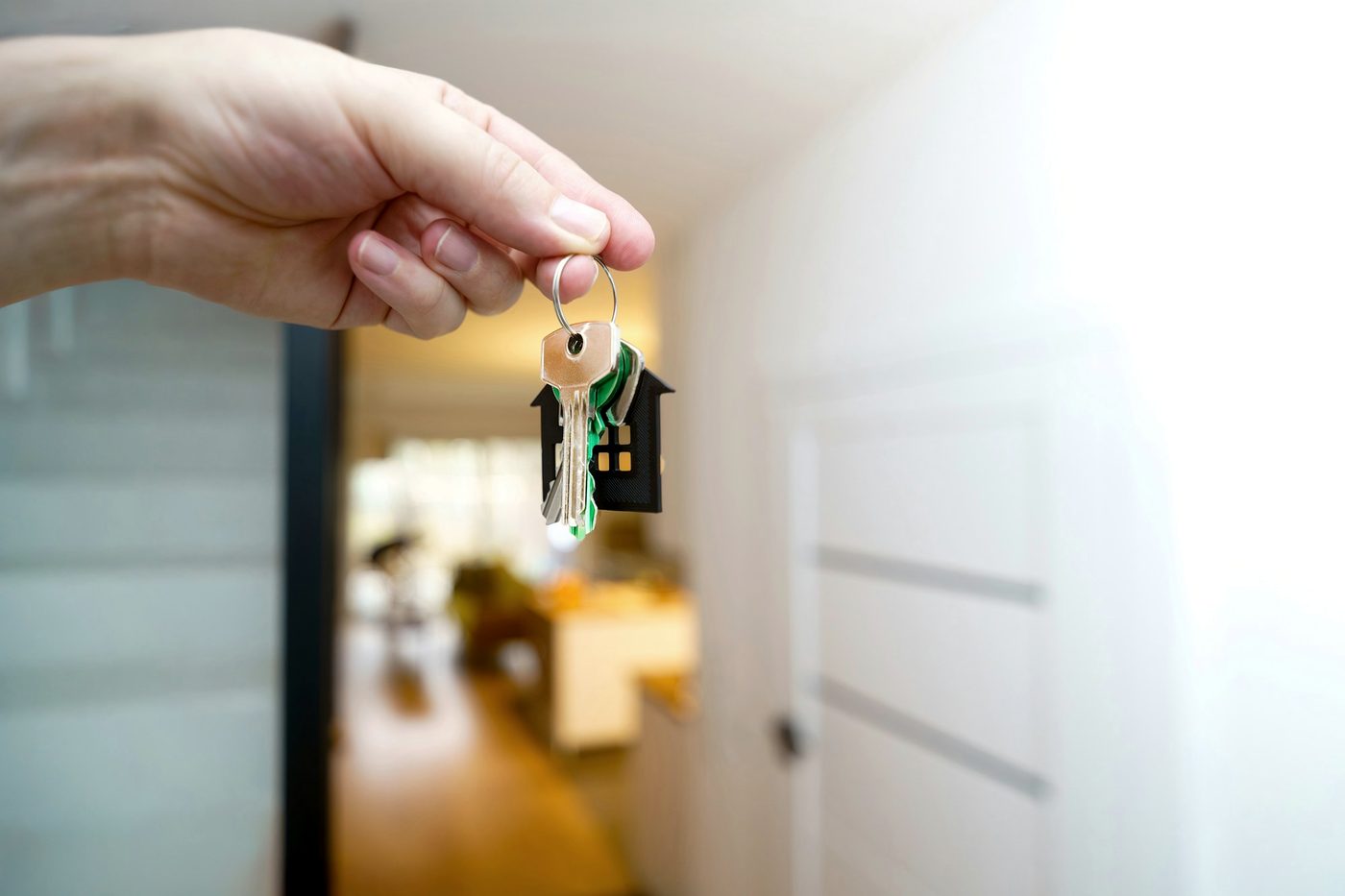 A hand holding a set of house keys in a hallway.
